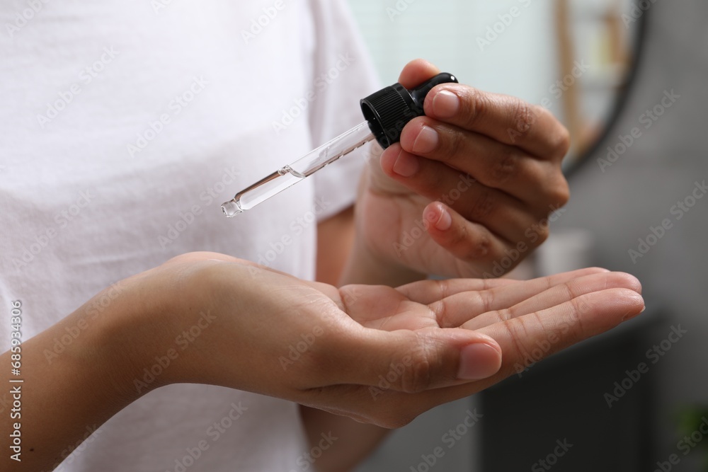 Woman applying cosmetic serum onto her hand on blurred background, closeup Woman applying cosmetic serum onto her hand on blurred background, closeup