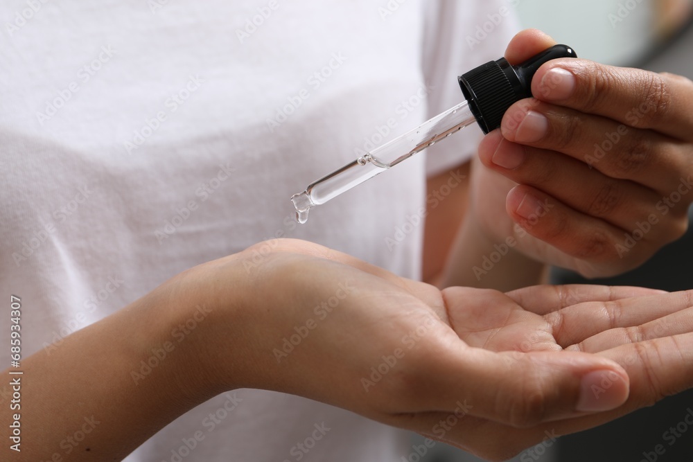 Woman applying cosmetic serum onto her hand, closeup Woman applying cosmetic serum onto her hand, closeup