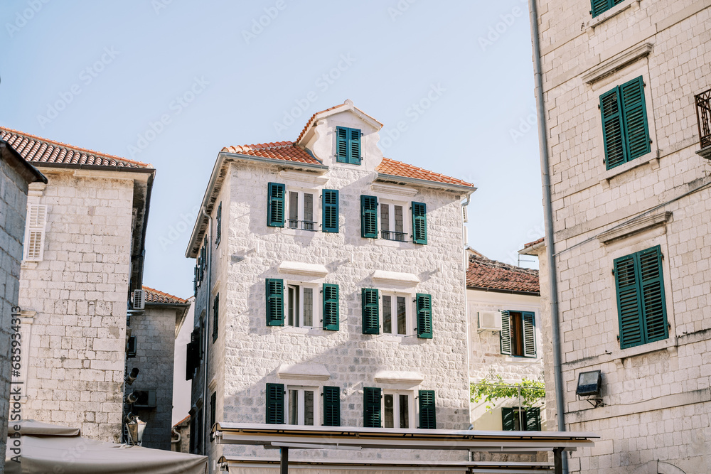 Ancient stone houses on a narrow street with green shutters. Kotor, Montenegro