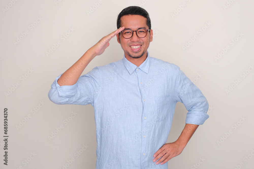 Adult Asian man smiling while giving salute Adult Asian man smiling while giving salute