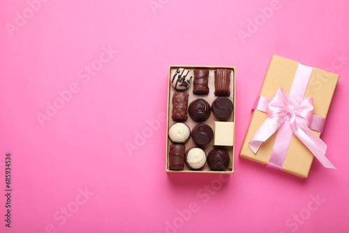 Open box with delicious chocolate candies on pink background, top view. Space for text © New Africa