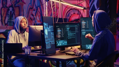 Hackers devising plan together, coding malware designed to exploit network backdoors, bypassing security measures such as logins and password protections in graffiti painted bunker photo