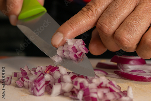 Finger pushing cut red onion on a kitchen board. Chef in the kitchen cutting vegetables in a kitchen table.