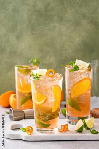 Orange and lime mojito cocktail in tall glasses with lime and mint