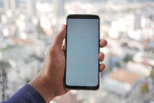  young man using smart phone with empty screen against city background 