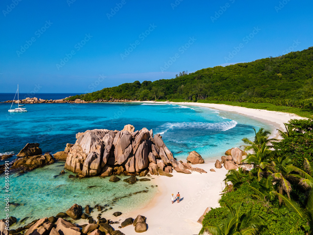 Anse Cocos beach, La Digue Island, Seychelles, Drone aerial view of La Digue Seychelles bird eye view of a tropical Island, couple men and woman walking at the beach during sunset at a luxury vacation