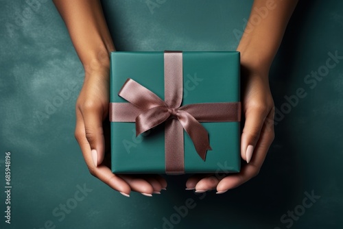 Hands holding dark green gift box and red ribbon top view, Christmas concept. Generative AI.