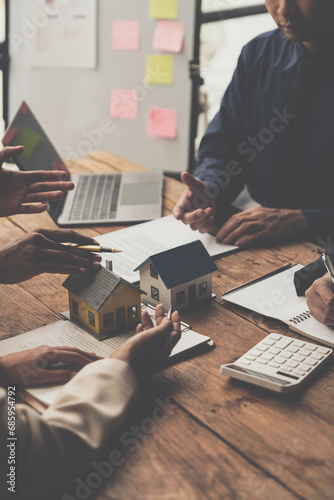 Entrepreneurs, business owners, accountants and real estate agents meet, discuss and use calculators to calculate budgets for purchasing a home project and calculate financial risks for clients.