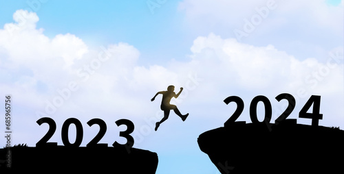Happy new year 2024. Man silhouette jumping cliff from 2023 to 2024 on cloud sky background.