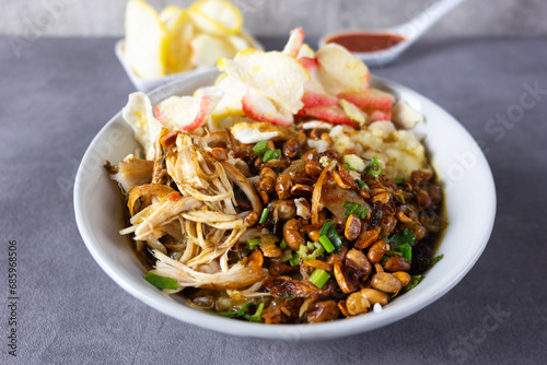 Bubur ayam or Chicken Porridge, Indonesian traditional food consist of white rice porridge, shredded chicken, fried soybean, crackers, leek. photo