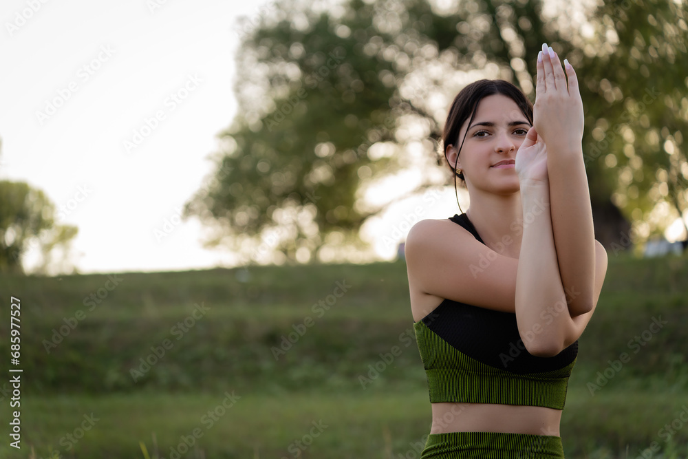A young girl turned to the camera and holding her hand in front of her reveals inner strength doing yoga in nature. A young girl turned to the camera and holding her hand in front of her reveals inner strength doing yoga in nature.