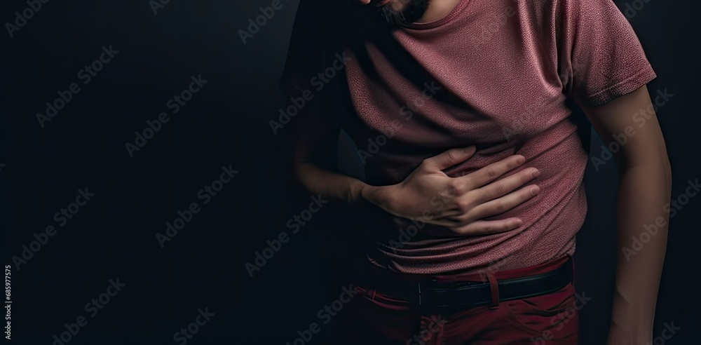 Young caucasian man holding stomach in pain. Digestive distress. Unwell adult suffering from stomachache and discomfort