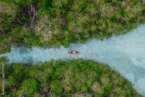 aerial of people kayaking in clear blue water surrounded by mangrove forest