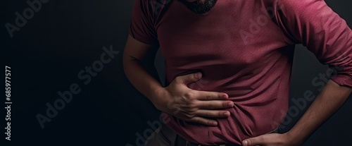 Young caucasian man holding stomach in pain. Digestive distress. Unwell adult suffering from stomachache and discomfort photo