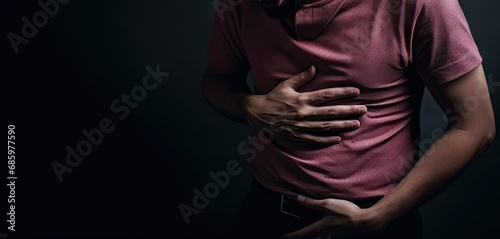 Young caucasian man holding stomach in pain. Digestive distress. Unwell adult suffering from stomachache and discomfort photo