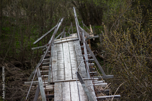 A wooden suspension bridge in the countryside distorted after a spring flood photo