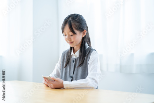 部屋で携帯を触る日本人の若い女の子