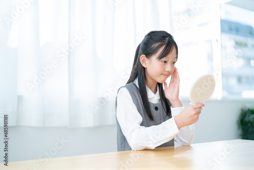 自宅で手鏡を見る若い日本人の女の子