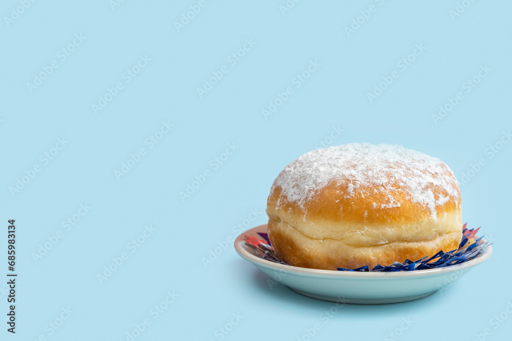 Traditional doughnut Sufganiyah for Jewish holiday Hanukkah on blue background with copy space. Traditional doughnut Sufganiyah for Jewish holiday Hanukkah on blue background with copy space.