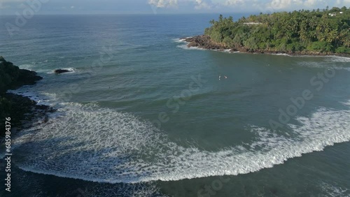 Establishing Aerial Drone Shot Over Bay in Tropical Sri Lanka with Surfers in the Water photo