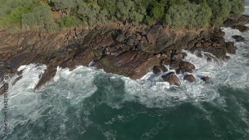 Slow Motion Aerial Drone Shot of Small Waves Crashing into Rocky Coastline in Tropical Sri Lanka photo