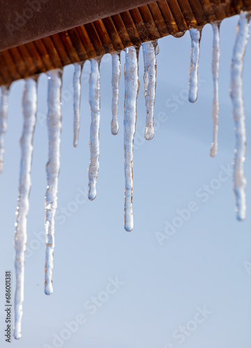 Icicles hang from the roof against the blue sky