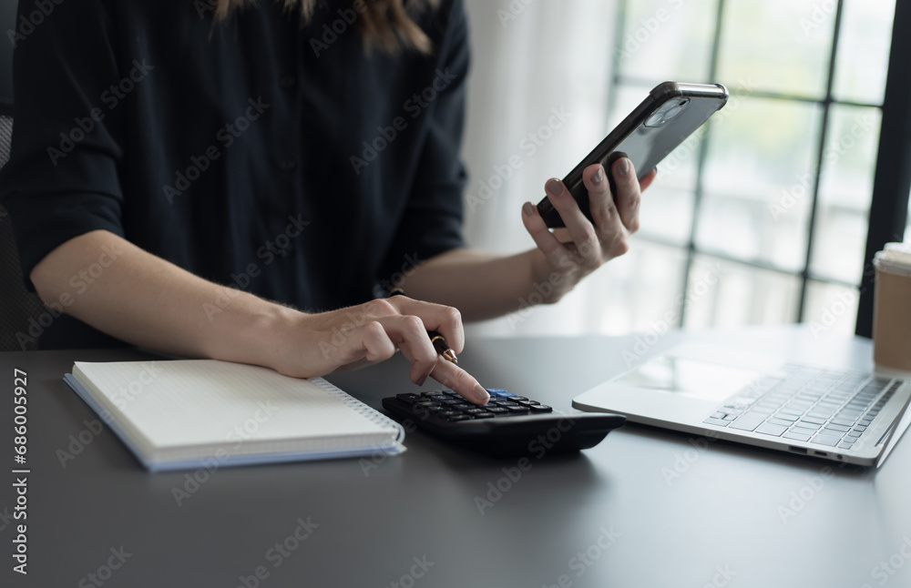 Fototapeta premium Happy businesswoman using a smartphone and sitting at desk in office.