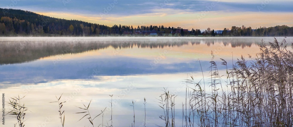 reflection sunset on the water of a lake  in the mist - sweden.