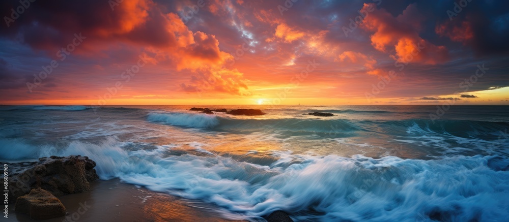 Stunning sunset or sunrise over the ocean with colorful dramatic skies, clouds, waves, and beautiful light.