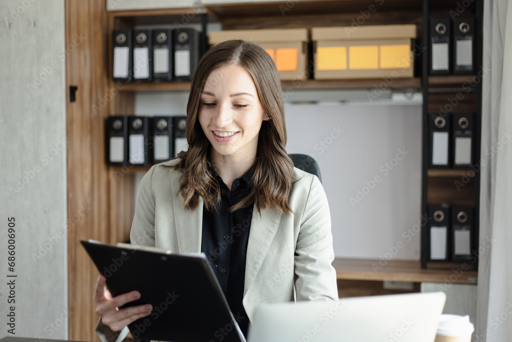 Happy businesswoman using a laptop computer and sitting at desk in office.