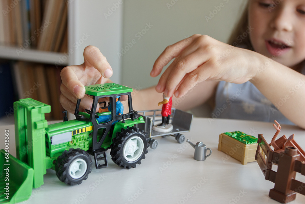 Cute child plays with farm equipment toys. Business or farming concept