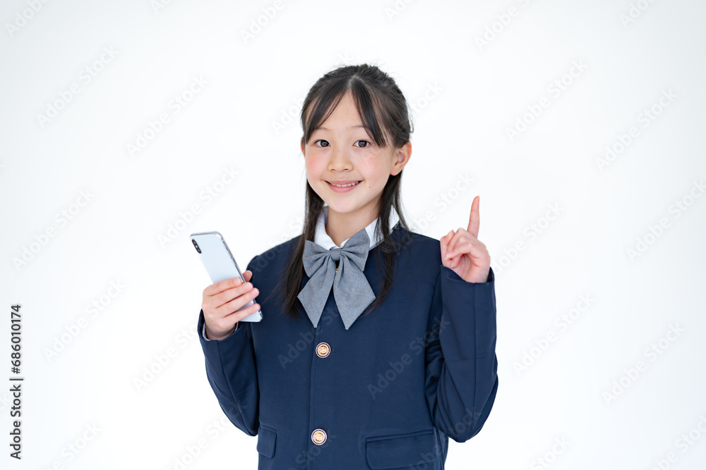 白背景で携帯を触る学生服を着た日本人の女の子