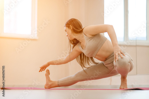 Girl does yoga. Young woman practices asanas on a beige one ton background.
