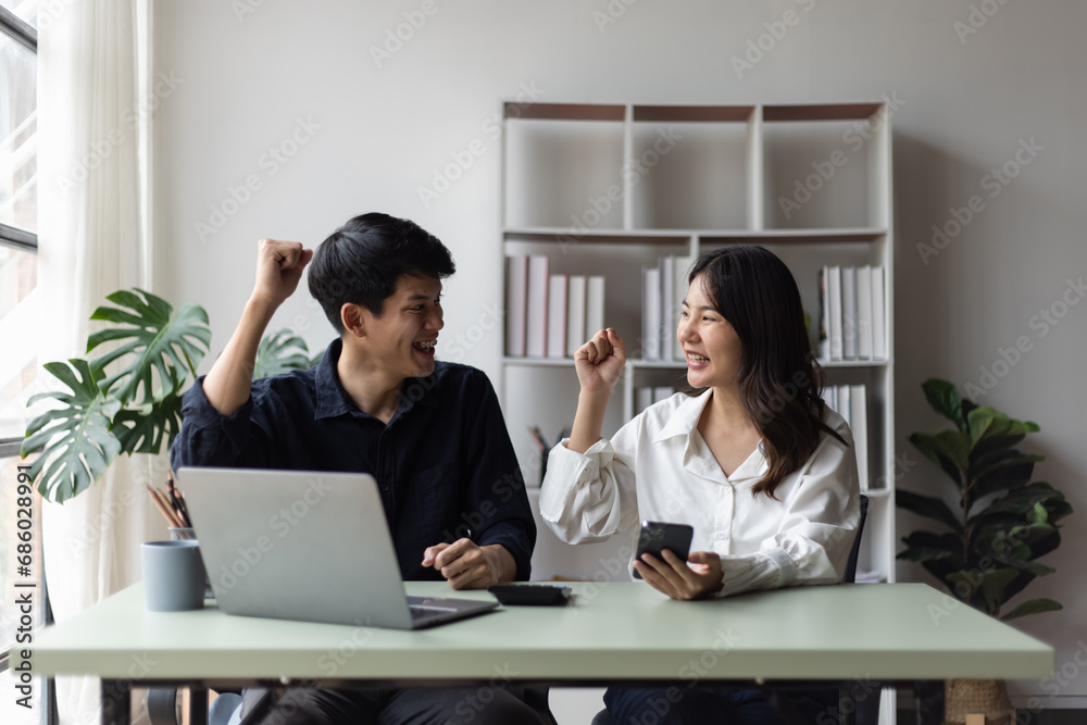 Two asian young businesswoman and man using laptop with documents in office working space. Two asian young businesswoman and man using laptop with documents in office working space.