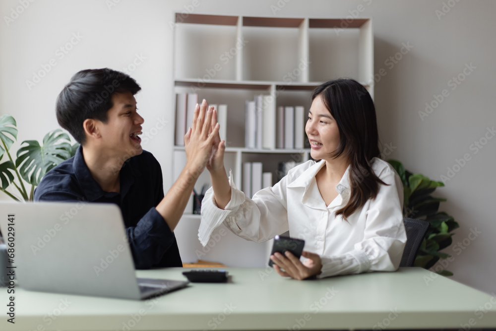 Two asian young businesswoman and man using laptop with documents in office working space. Two asian young businesswoman and man using laptop with documents in office working space.