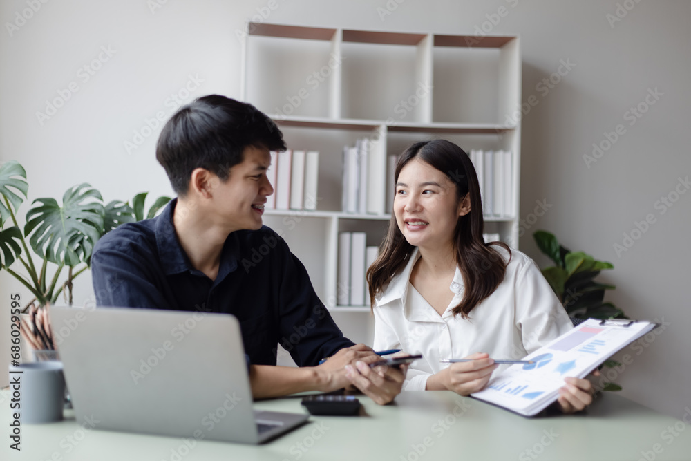 Two asian young businesswoman and man using laptop with documents in office working space. Two asian young businesswoman and man using laptop with documents in office working space.
