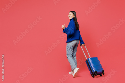Happy traveler woman wears blue sweater casual clothes hold bag walk isolated on plain pastel pink background. Tourist travel abroad in free spare time rest getaway. Air flight trip journey concept.. #686035786