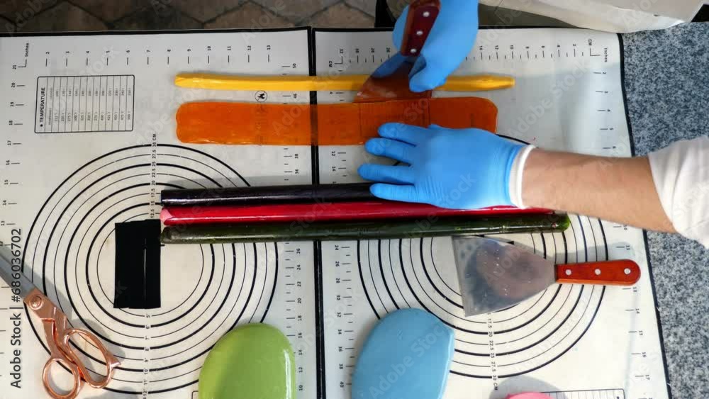 The process of creating handmade candies and lollipops, confectioners lay out rolled soft caramel forming a pattern. Creating small candies with a pattern inside. Top view.