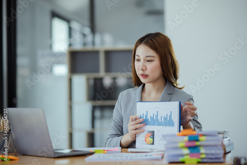 Asian businesswoman discuss new project investment plans and strategies for making business profits with laptop sitting at workplace in modern office.