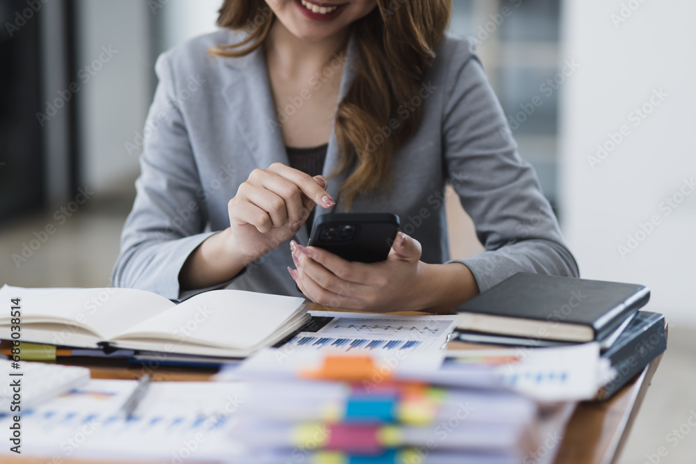 Accounting asian woman use smartphone and laptop at office desk in office, Accounting businesswoman online working concept. Accounting asian woman use smartphone and laptop at office desk in office, Accounting businesswoman online working concept.