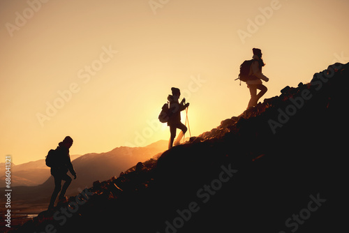 Group of hikers with backpacks walks uphill in sunset mountains © cppzone