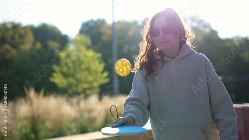 Female juggling with a pickleball on court outdoors