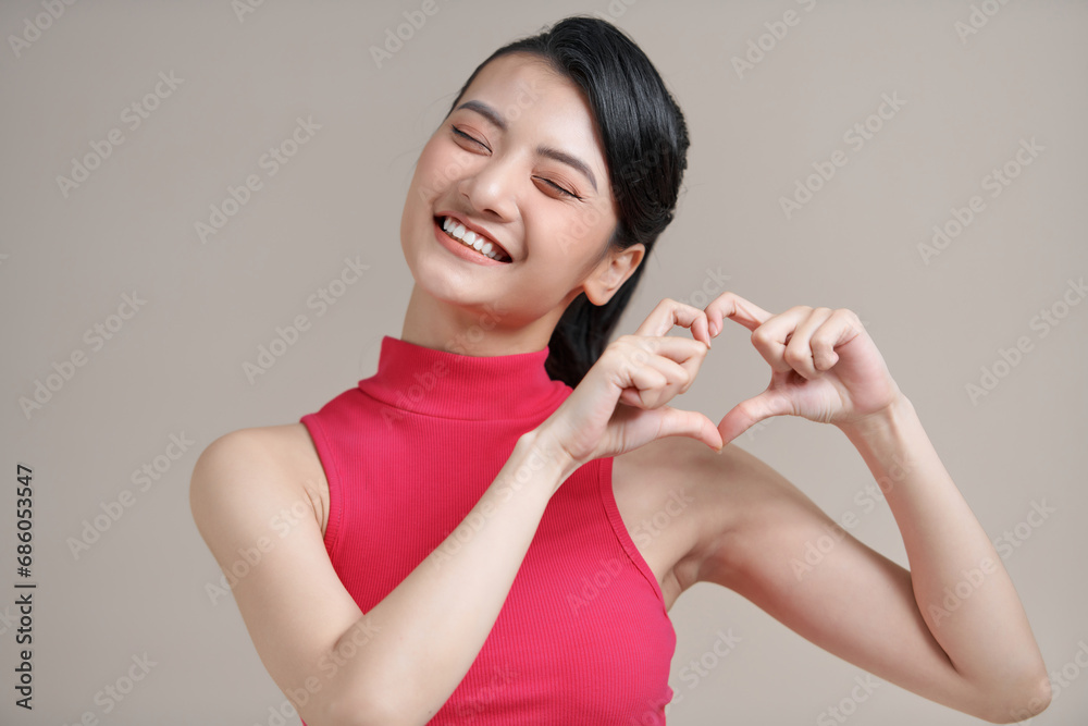 Pretty romantic young asian woman making a heart gesture with her fingers in front of her chest Pretty romantic young asian woman making a heart gesture with her fingers in front of her chest