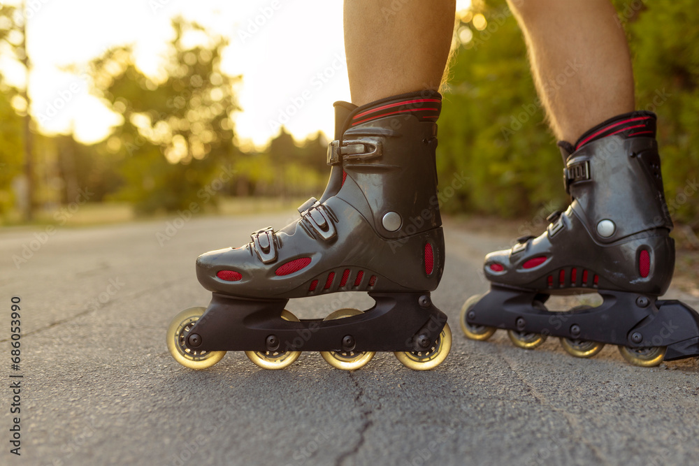 unrecognizable feet with rolling skate close up on rural paved street with sun flare or back light low angle view