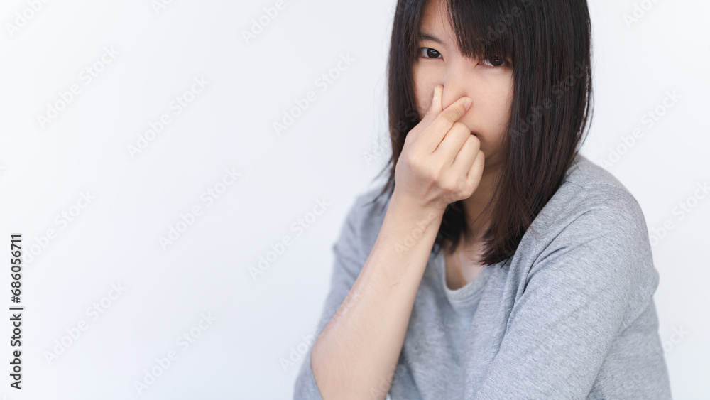 Asian woman covers her nose because she smells a bad smell. Asian woman covers her nose because she smells a bad smell.