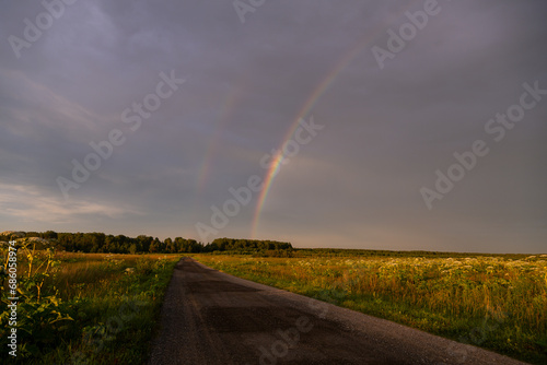 Rainbow over a field road in summer