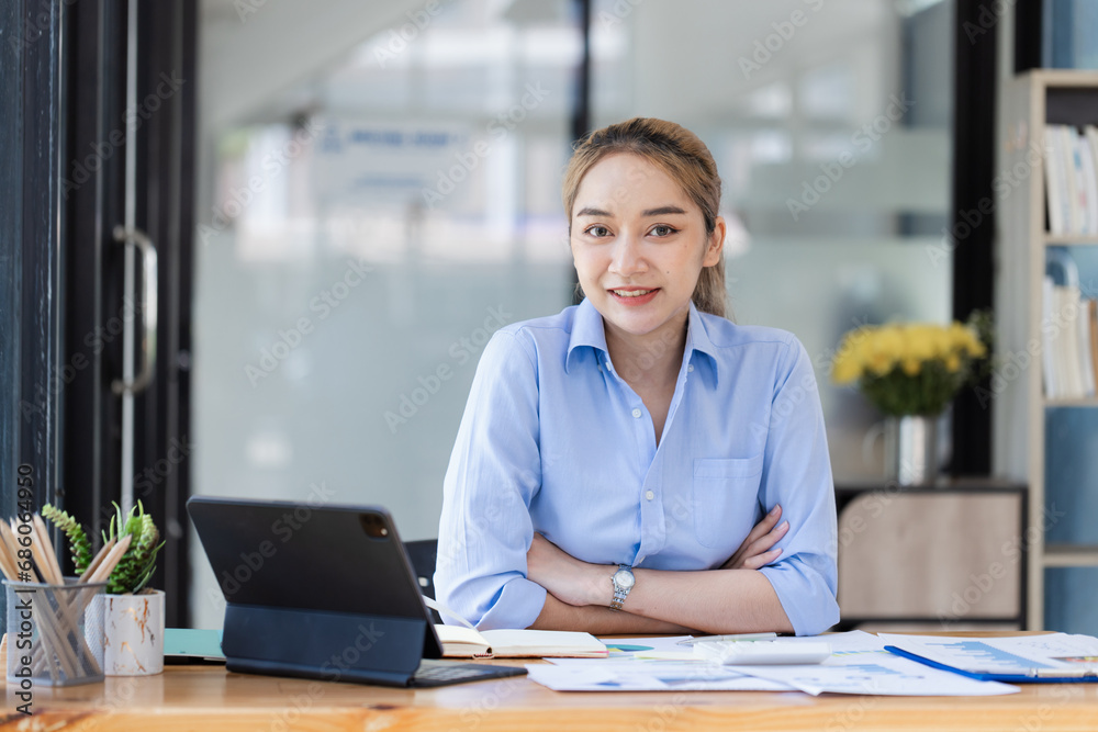 Happy smiling asian businesswoman working on tablet with document paper sitting at desk in office. Happy smiling asian businesswoman working on tablet with document paper sitting at desk in office.