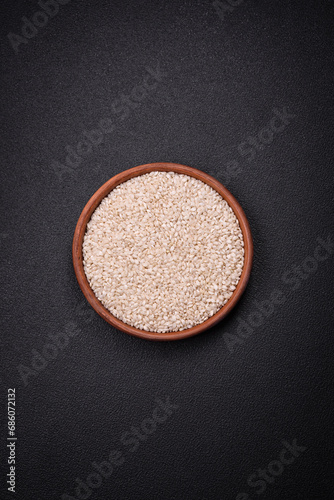 White uncooked rice in a round ceramic bowl on a dark concrete background