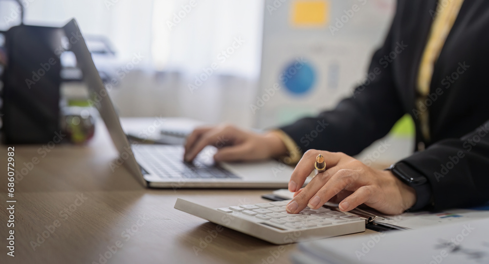 Businesswoman accountant using calculator and laptop for financial data saving in office room, Business financial, tax, accounting concept Businesswoman accountant using calculator and laptop for financial data saving in office room, Business financial, tax, accounting concept
