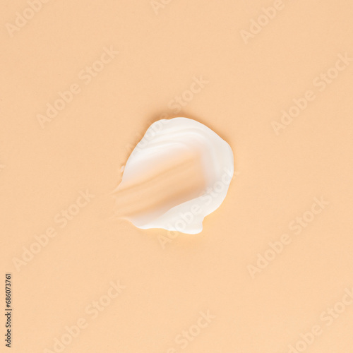 Smear of white cream for face and body on a brown background